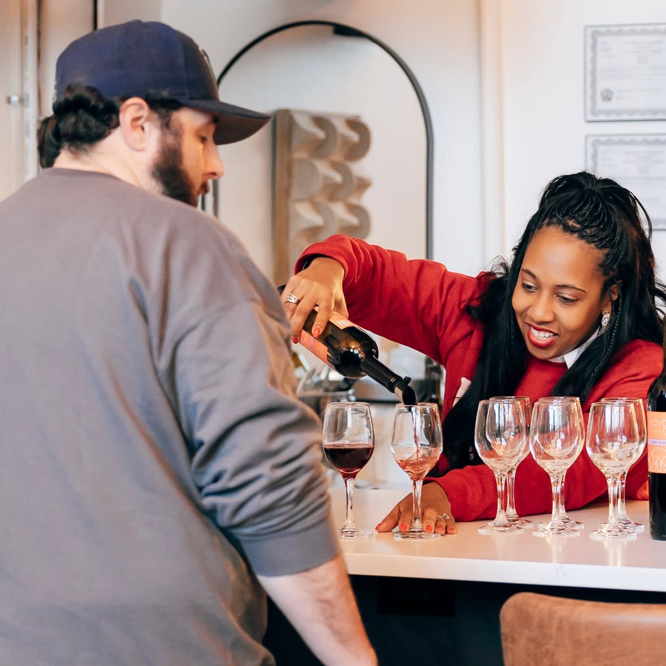 A tenant pours wine for a guest at a tasting bar